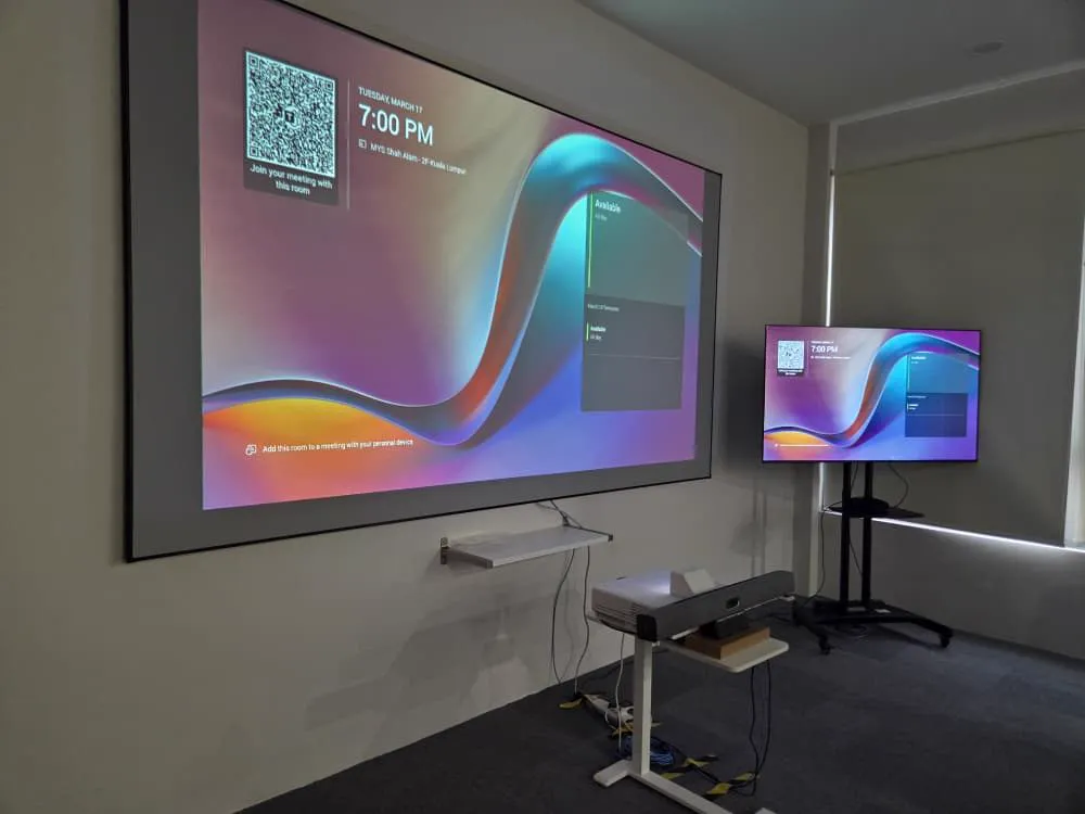 Ultra short throw projector on a fixed-frame screen beside a mobile display