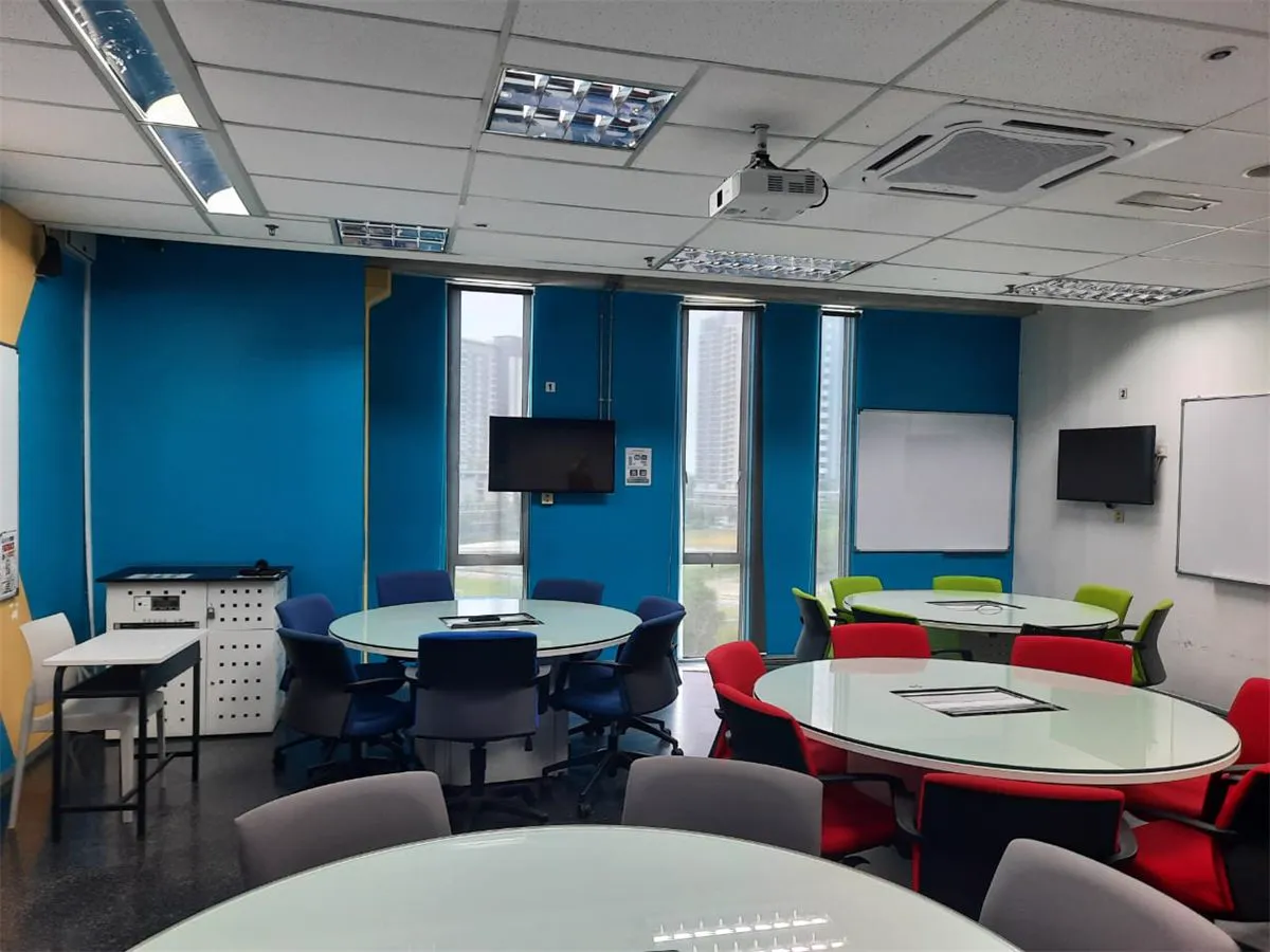 Collaborative classroom with round tables and wall-mounted displays